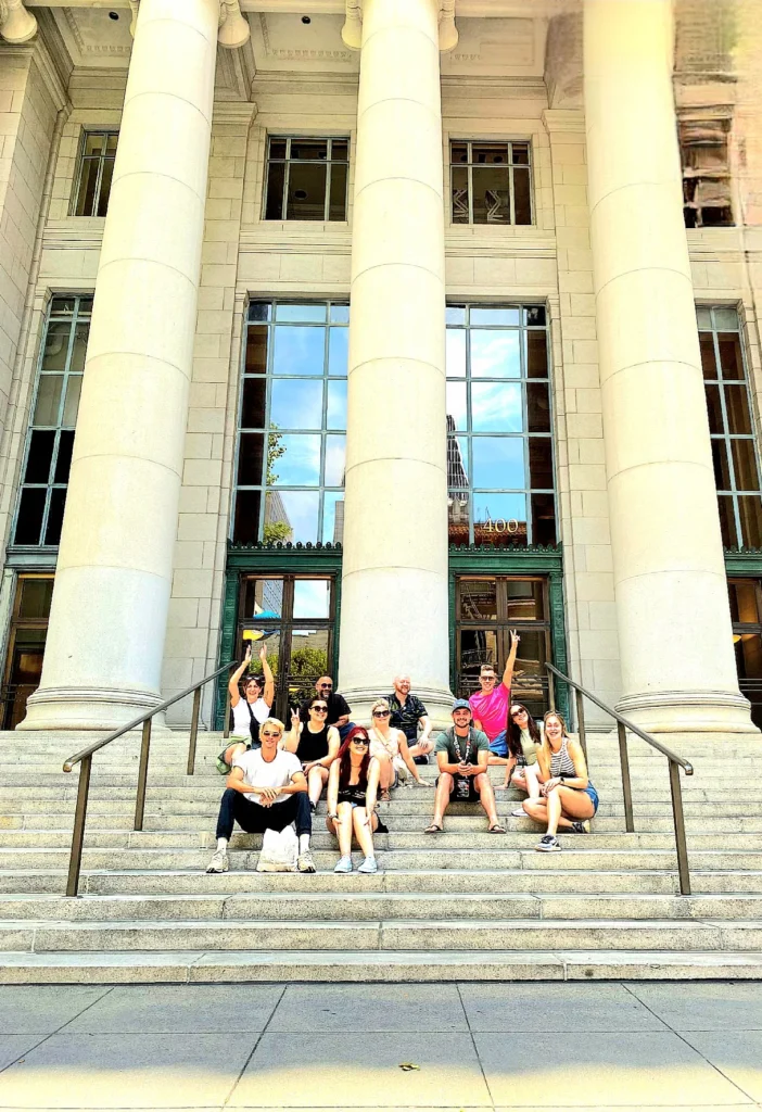 Tour group smiling on the grand steps of a classical building in San Francisco Financial District