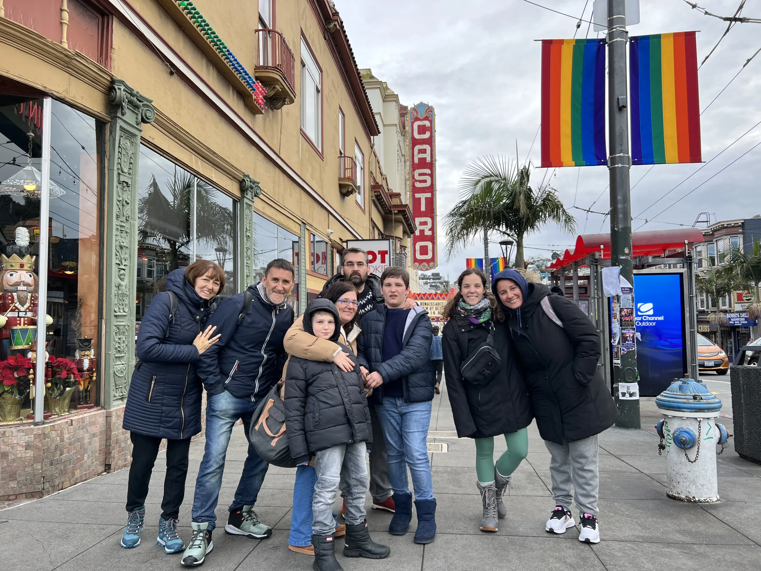 Smiling group on Castro Street, San Francisco, with theatre sign and rainbow flag