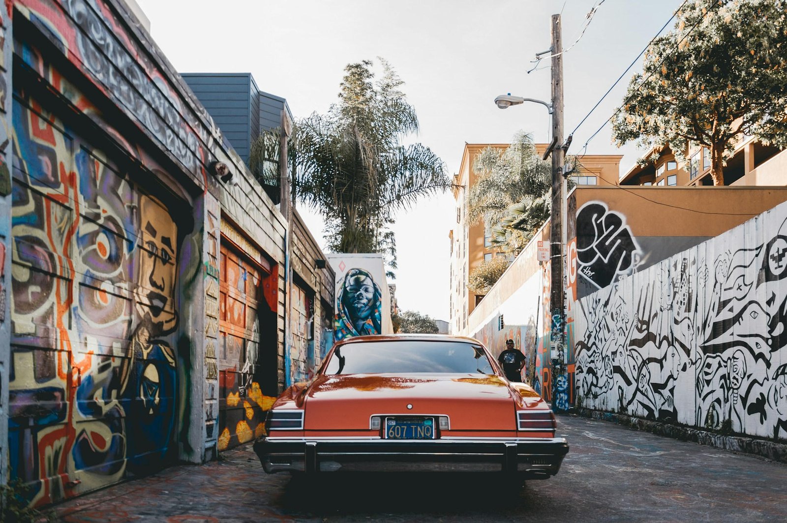 Classic car parked in a colorful urban alley with graffiti murals